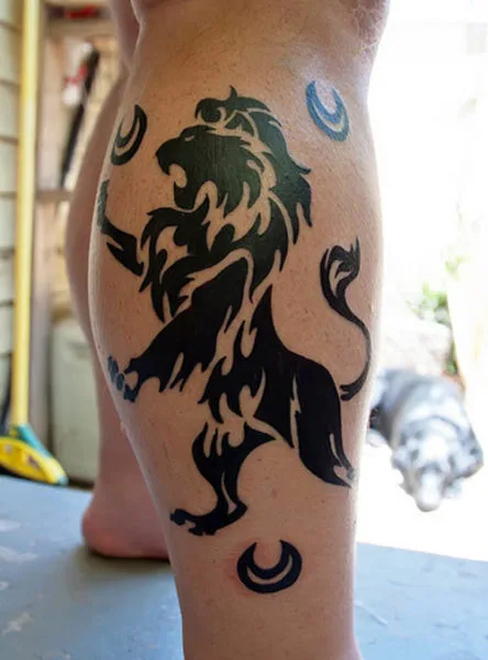 Black and grey lion tattoo on the calf