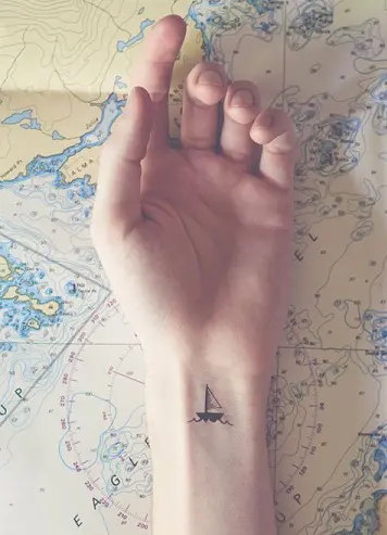 Black outlined small earth with airplane tattoo on wrist