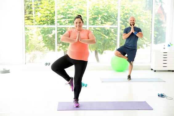 Overweight,man,and,woman,practicing,yoga,in,gym