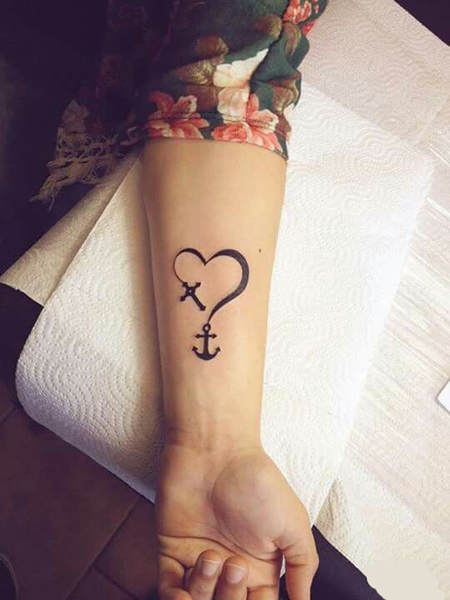 Black cross with heart tattoo on inner left lower arm for women