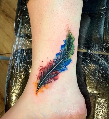 Large rose and feather tattoo located on the forearm