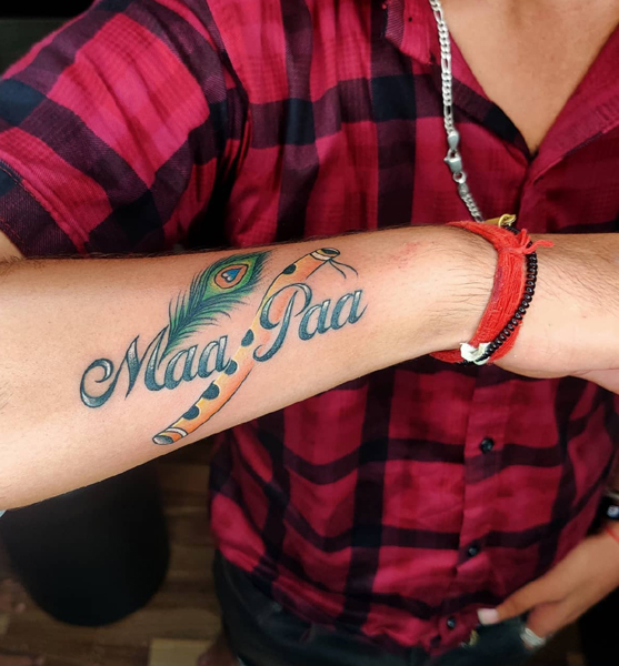 Maa Paa Tattoo With A Flute And Peacock Feather