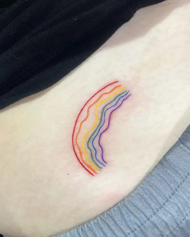 Small rainbow tattoo on the left tricep