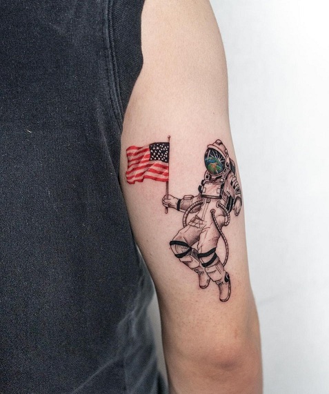 Astronaut Holding American Flag Bicep Tattoo