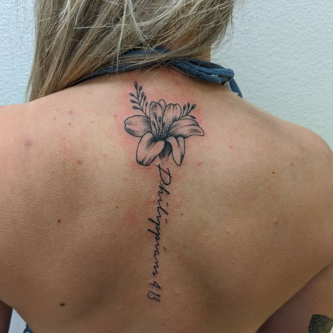 Bible verse tattoo on the back with a flower