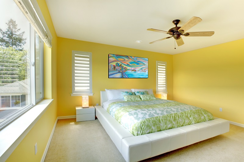 Yellow,bright,bedroom,with,green,bedding,and,white,bed.